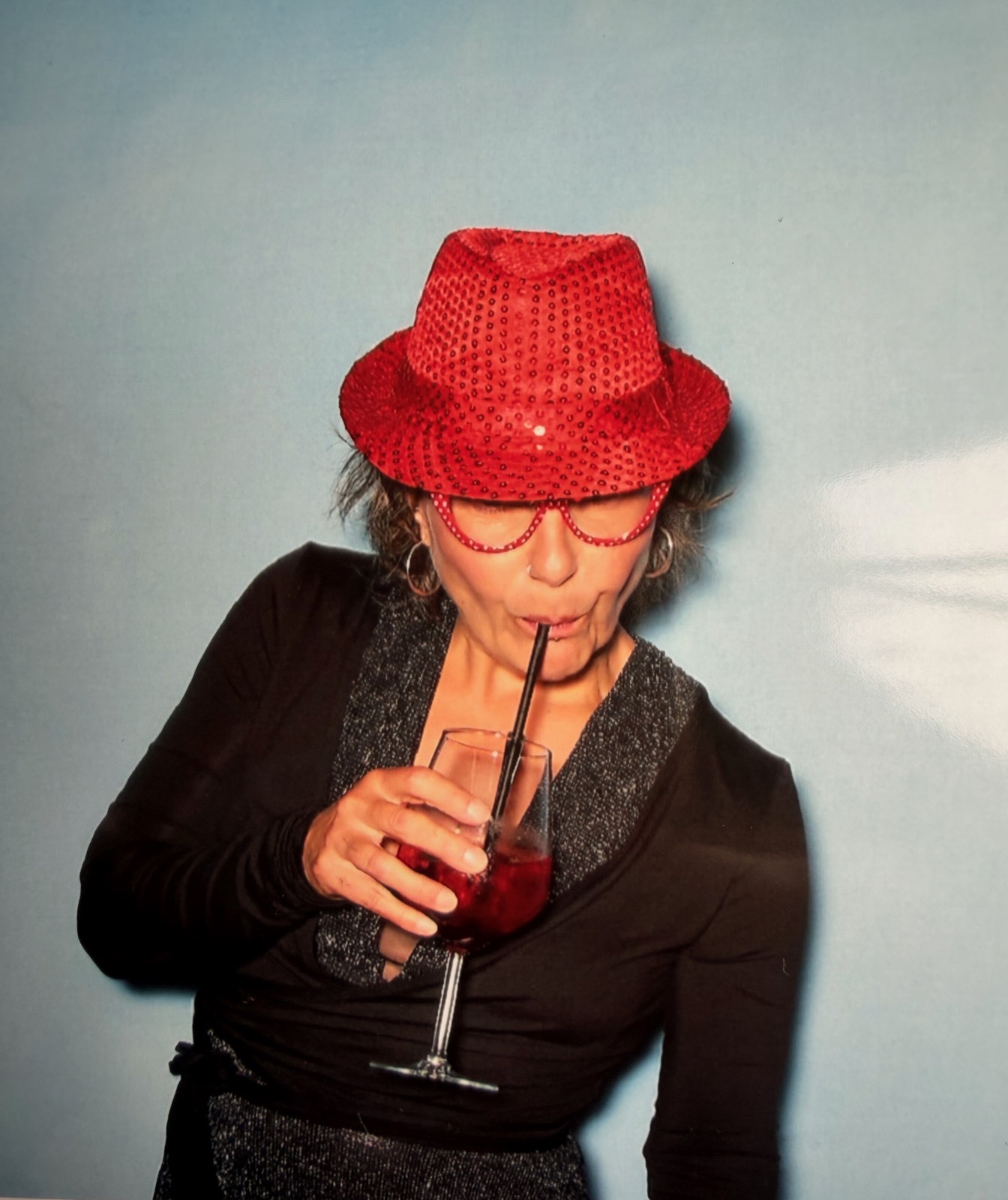 Inga mit rotem Glitzerhut und Cocktail in der Photobooth